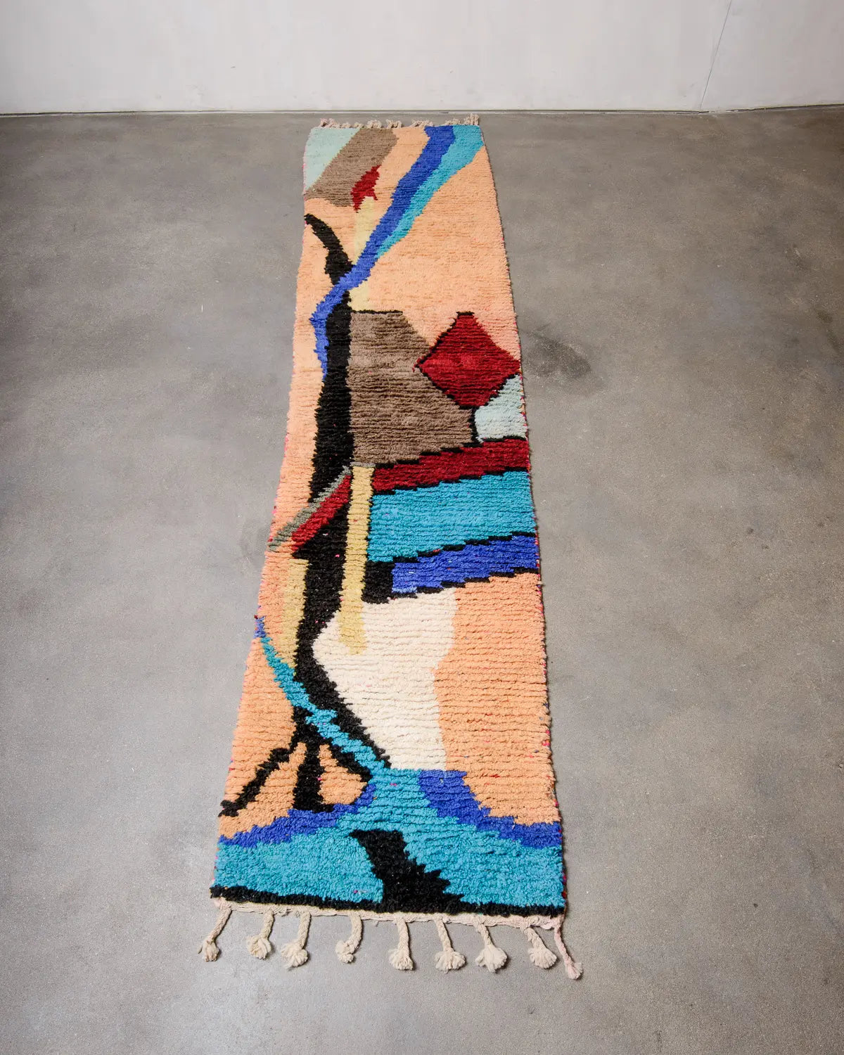 Wool Berberlin runner rug laying flat on grey concrete floor.